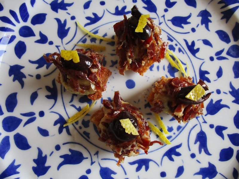 Fried spelt-flour bread pinchos carry an artichoke cream, cured ham fragments, pitted black olives and lemon zest.