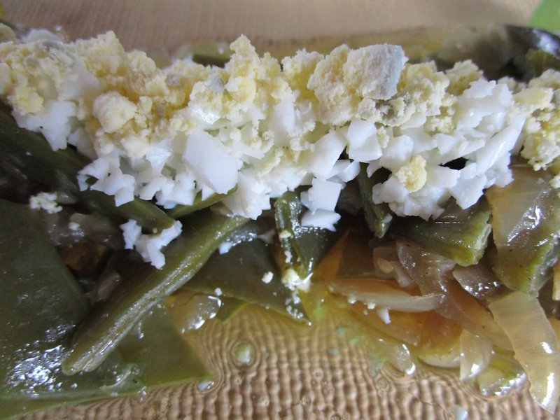 Stripes of chopped hard-boiled egg add protein to green beans tossed in onion oil. Stripes of chopped hard-boiled egg add protein to green beans tossed in onion oil.