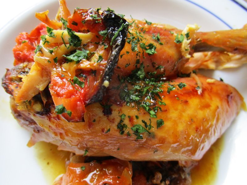 Crispy-skinned paper-wrapped roast chicken and tomatoes.